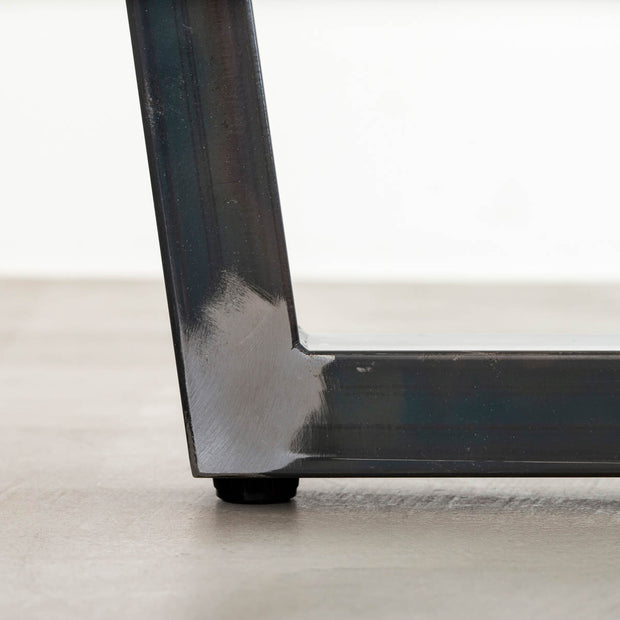 KANADEMONOの配線孔BROCK&TRAY付きのラバーウッド材ナチュラル天板とマットクリア塗装仕上げのブラックのトラぺゾイド鉄脚を組み合わせたテーブル（アジャスター部分）