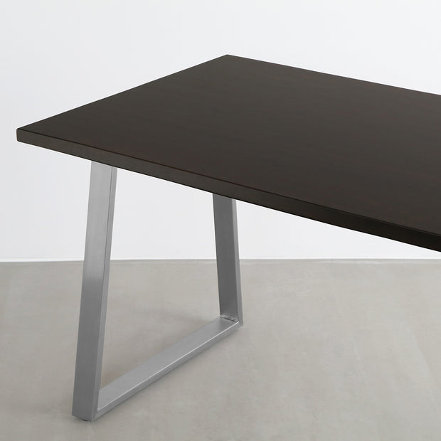 Gemoneのシックなブラックブラウンのラバーウッド材と美しい質感が際立つベル型ステンレス脚を組み合わせた重厚感のあるテーブル（斜め）