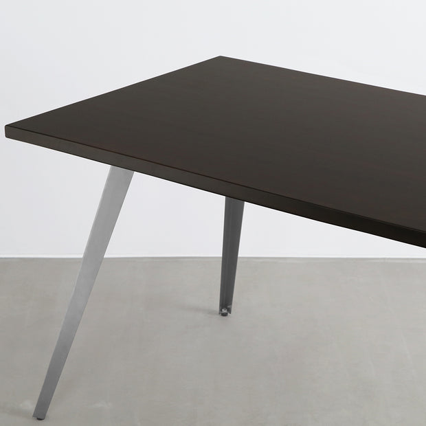 Gemoneのシックなブラックブラウンのラバーウッド材と美しい質感が際立つフラットピンのステンレス脚を組み合わせた重厚感のあるテーブル(斜めからのアングル)