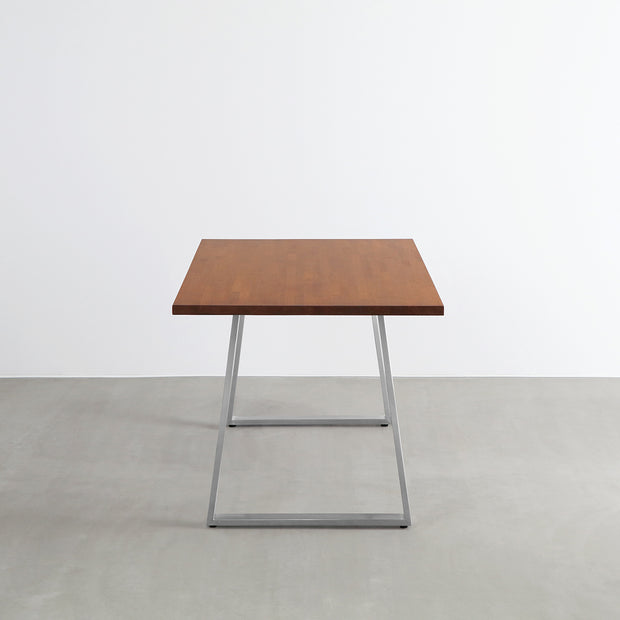 Gemoneの艶やかなチークブラウンのラバーウッド材と美しい質感が際立つベル型ステンレス脚を組み合わせた重厚感のあるテーブル（横向き）