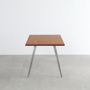 Gemoneの艶やかなチークブラウンのラバーウッド材と美しい質感が際立つフラットピンのステンレス脚を組み合わせた重厚感のあるテーブル(横からのアングル)