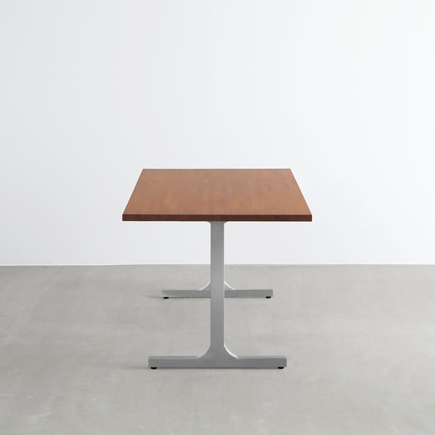 Gemoneの艶やかなチークブラウンのラバーウッド材と美しい質感が際立つI型のステンレス脚を組み合わせた重厚感のあるテーブル(横からのアングル)