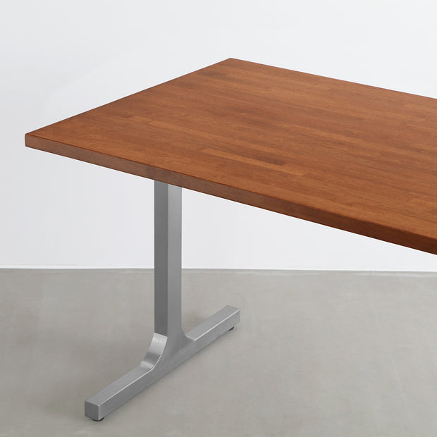 Gemoneの艶やかなチークブラウンのラバーウッド材と美しい質感が際立つI型のステンレス脚を組み合わせた重厚感のあるテーブル(斜めからのアングル)