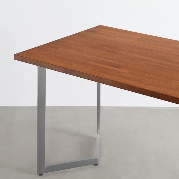 Gemoneの艶やかなチークブラウンのラバーウッド材と美しい質感が際立つW型ステンレス脚を組み合わせた重厚感のあるテーブル（斜め）