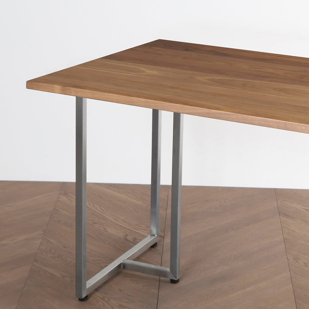 Gemoneのウォルナット天板とT型ステンレス脚を組み合わせた重厚感のあるテーブル（斜め向き・クローズアップ）