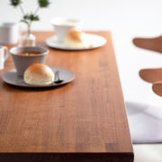 Gemoneの艶やかなチークブラウンのラバーウッド材と美しい質感が際立つスクエアのステンレス脚を組み合わせた重厚感のあるテーブル（使用例2）